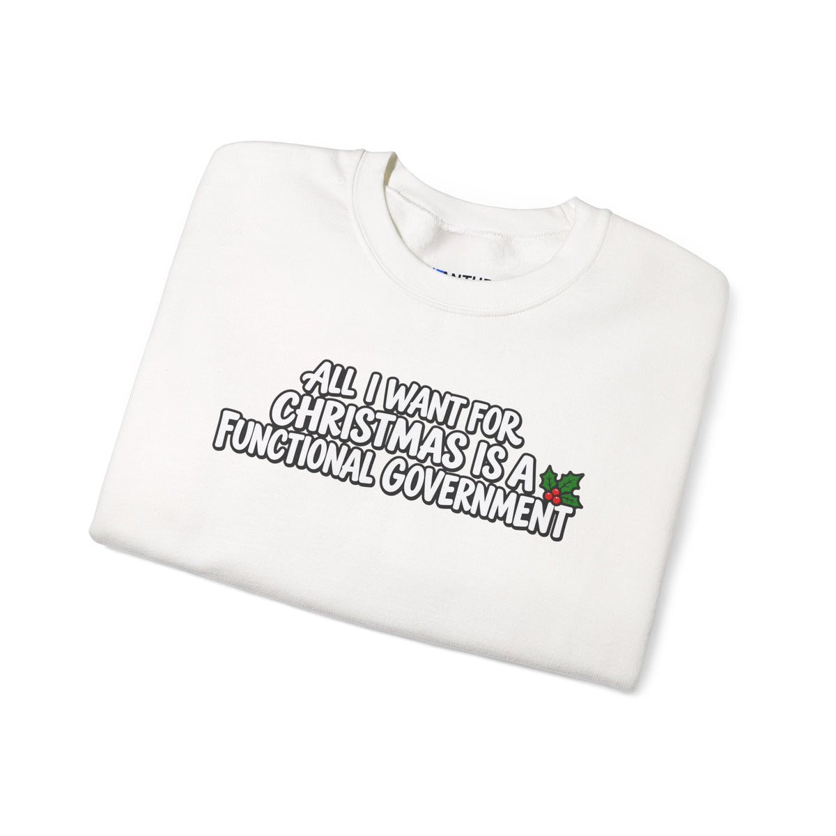 A folded white crewneck sweatshirt with a humorous graphic printed on the front. The graphic features the text 'ALL I WANT FOR CHRISTMAS IS A FUNCTIONAL GOVERNMENT' in a stylized black and white font, accented with a small green holly leaf with red berries on the right side