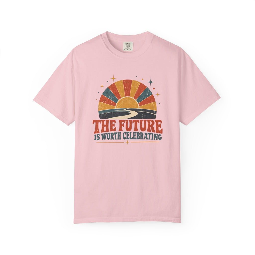 A light pink short-sleeve crewneck t-shirt featuring a retro sunset graphic with the text 'THE FUTURE IS WORTH CELEBRATING' printed on the chest.